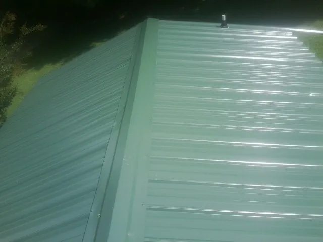 New green metal panels meeting at the ridge of a roof — Flat Roof Repair work by our crew in Willis
