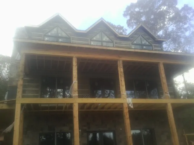 Dormers and porch framing on a large log home under construction — Roof Coating work by our crew in Willis